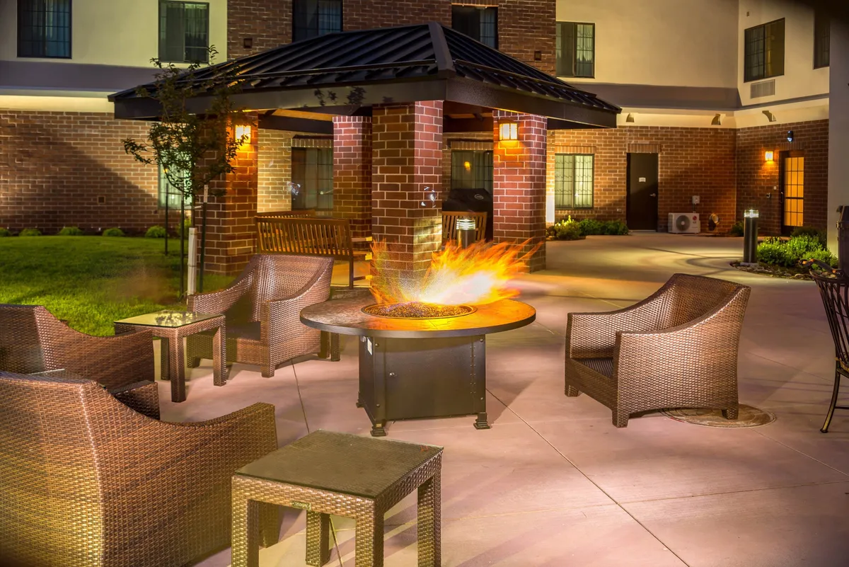 A warm and welcoming outdoor patio with a fire pit, comfortable seating arrangements, and a gazebo structure, ideal for social gatherings and evening relaxation.
